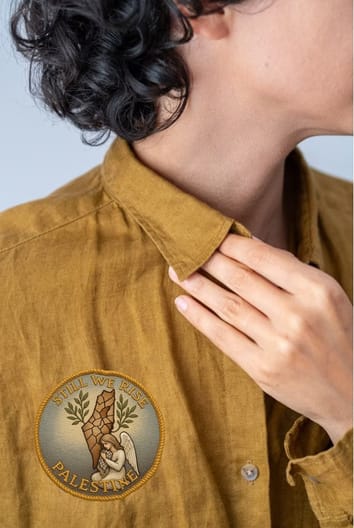 Close-up of a gold illustrated pin on a mustard jacket collar