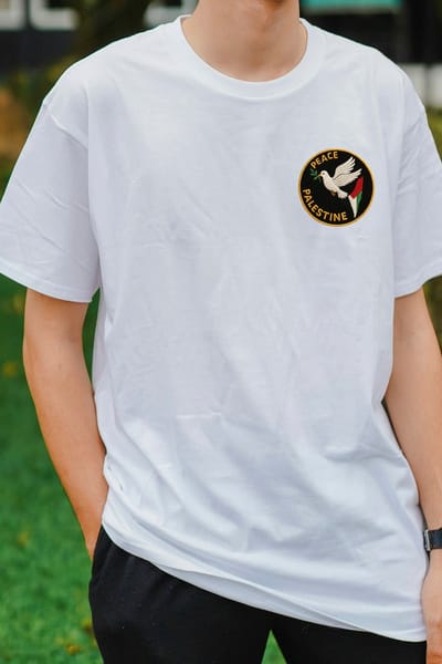 White T-shirt mockup with a small round dove badge on the chest